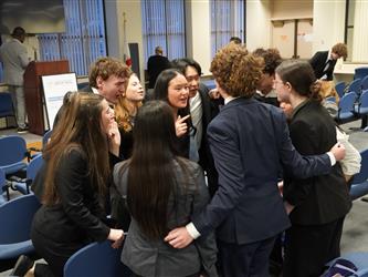 Students gathered in a room recite a team chant together at a mock trial competition.