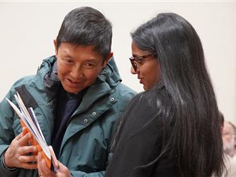 Adult coach or event volunteer speaks with a student participant while reviewing materials at a mock trial event.