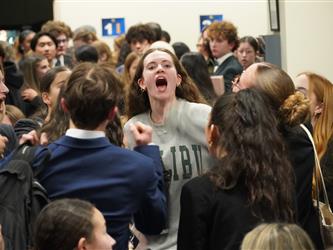 Students stand in a team huddle and recite a team chant together at a mock trial competition.