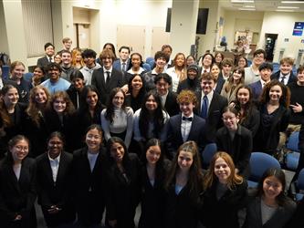 Large group of students in professional attire pose for a group photo following a mock trial event.