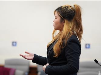 Student participant presents an argument during a mock trial proceeding, gesturing while speaking before the court.